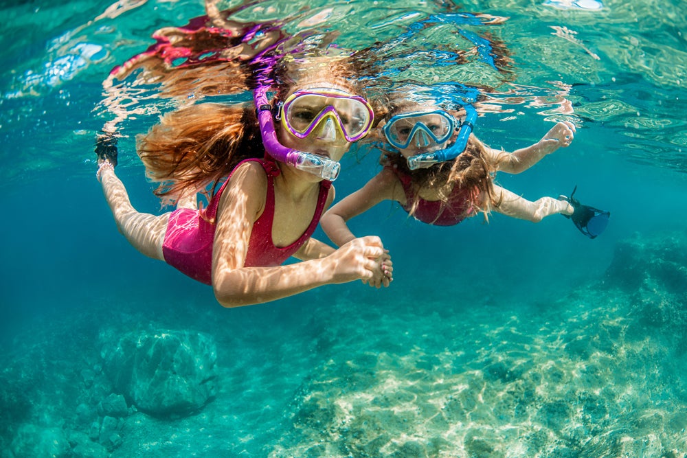 Dos personas practicando snorkel como uno de los deportes acuáticos